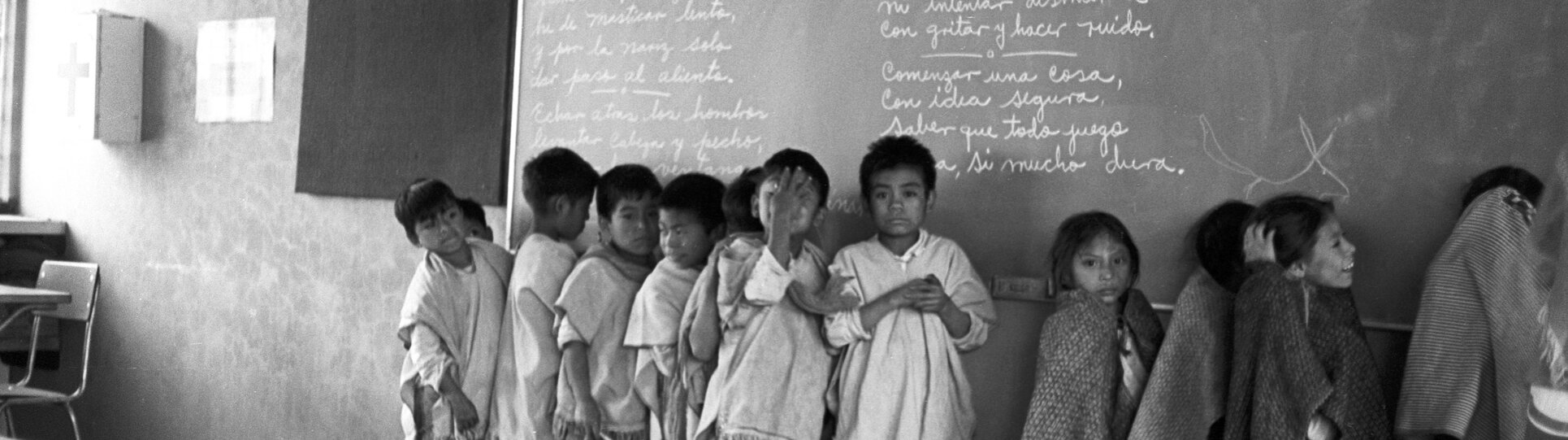 Detail of a black and white photograph of Maya children lined up by a blackboard